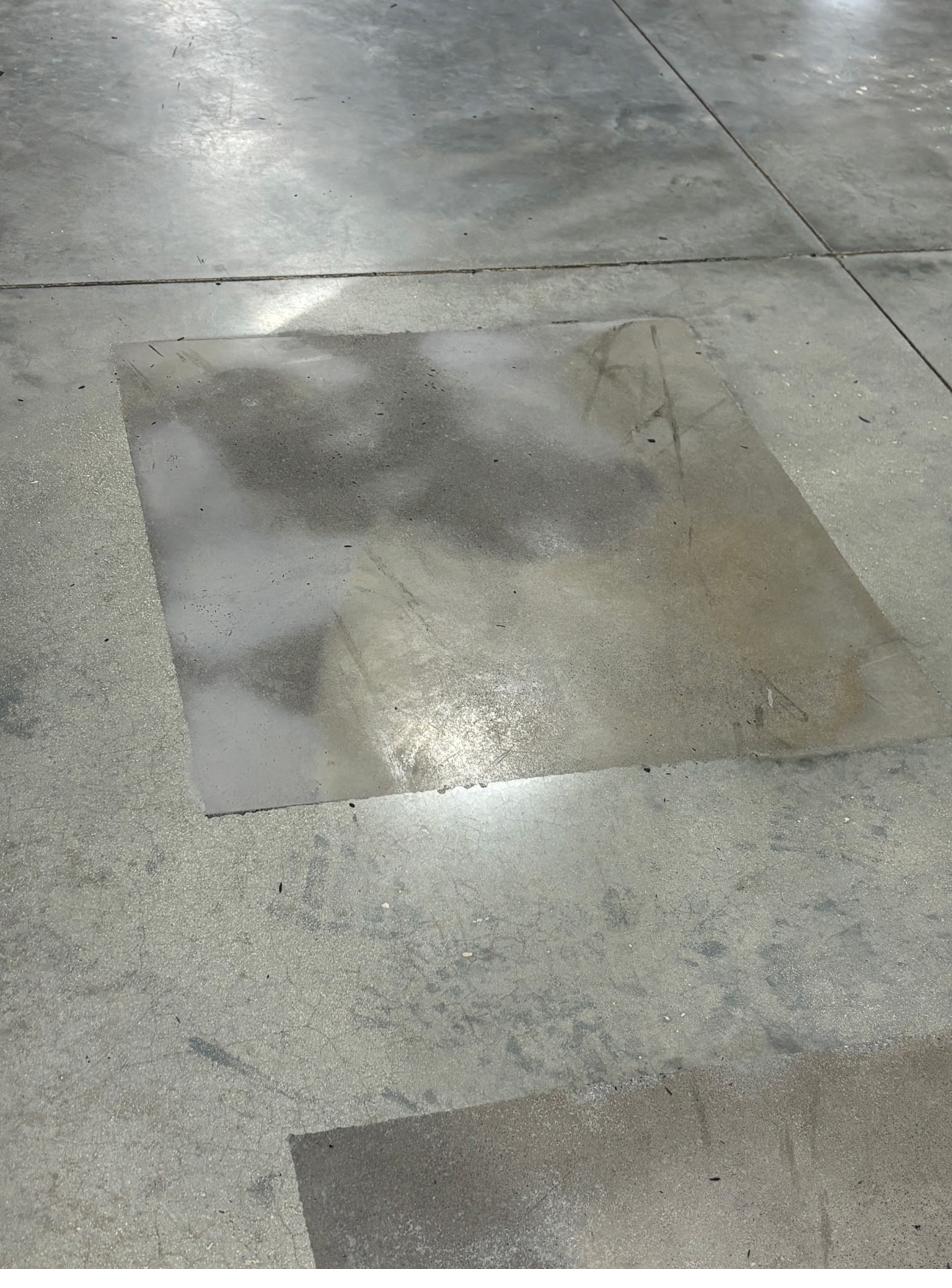 Concrete spall repair patch, ground flush with the slab